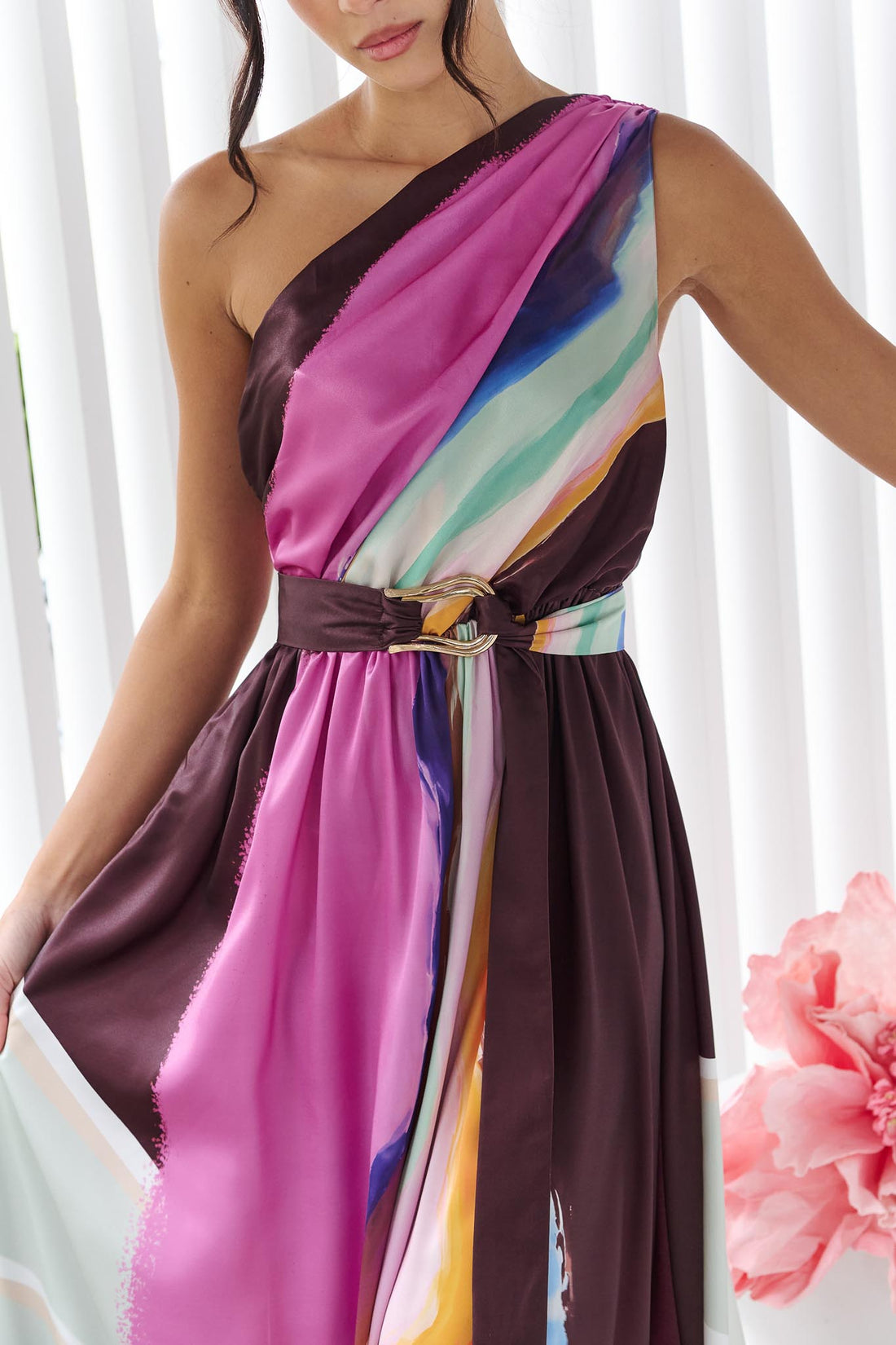 Detail of a woman wearing the minnie + MAXXIE Alessandra One Shoulder Maxi Dress with a graphic abstract print and matching waist tie.