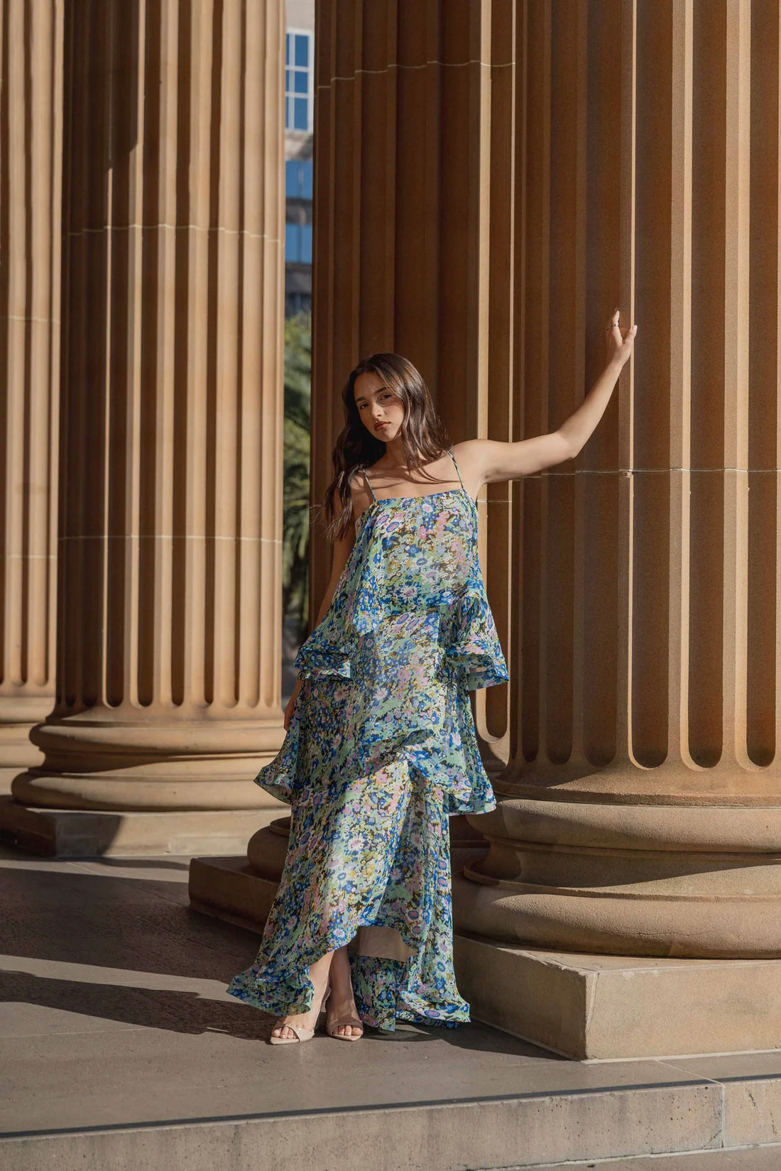 Woman in the Armani Tiered Maxi Dress in Blue Floral by ELLIATT standing on steps with classical architecture in the background