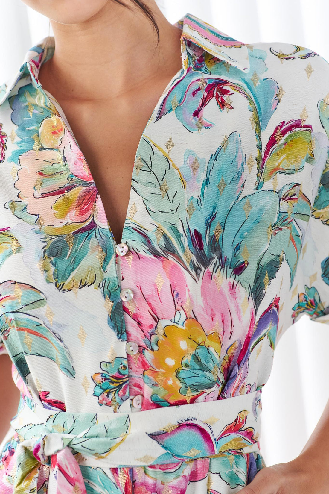 Detail of a woman wearing the minnie + MAXXIE short-sleeve Audrey midi dress with a colourful floral and paisley print.