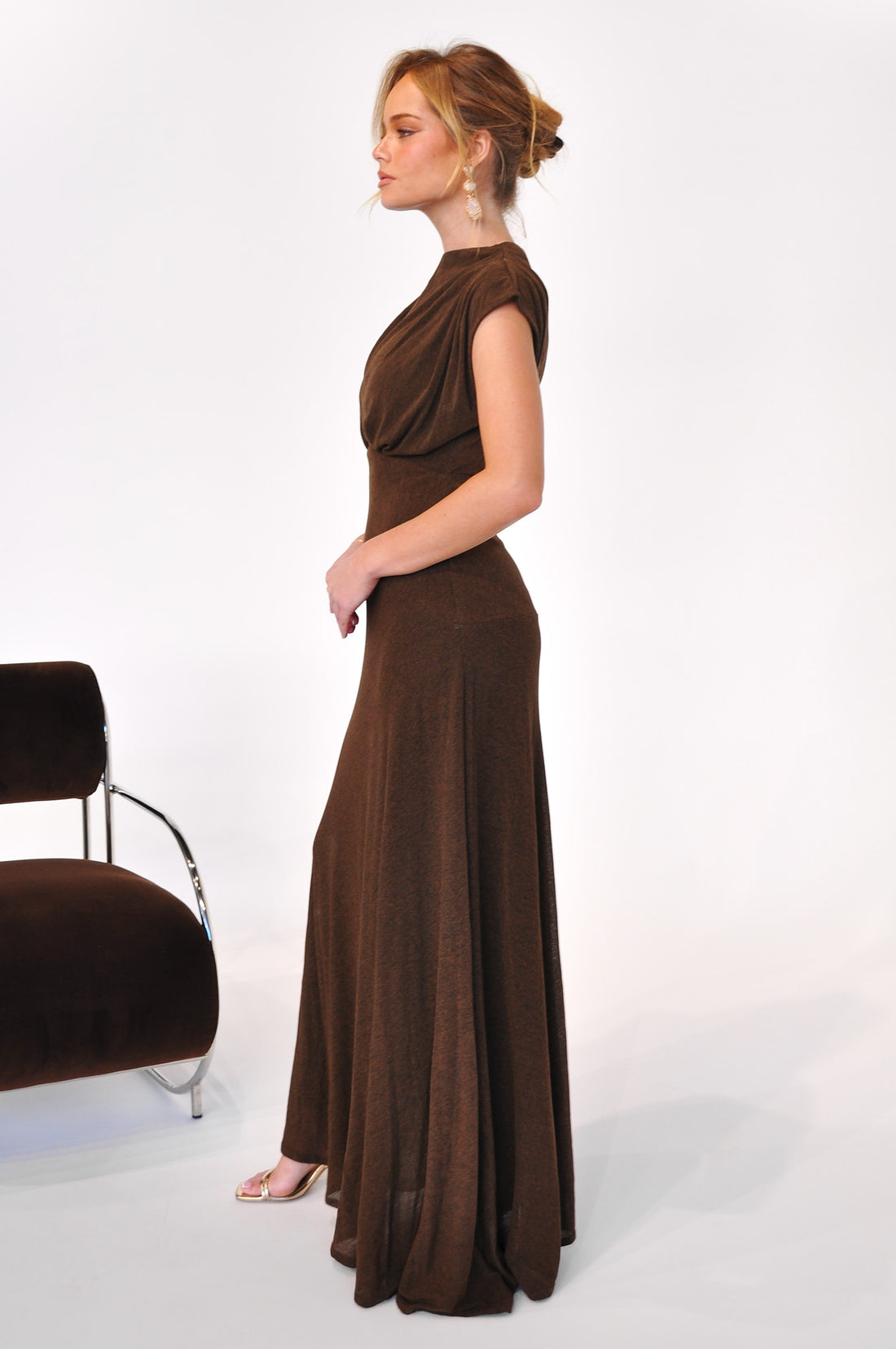 Woman wearing the Brigitte Gown, a cocoa brown maxi length event dress standing against a white background