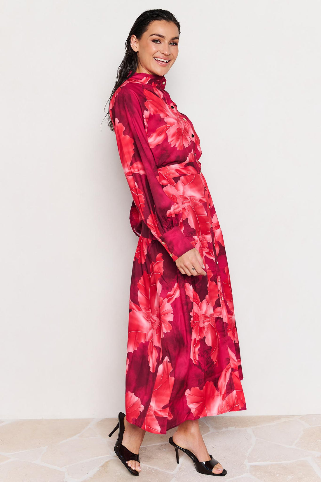 Side view of woman wearing the minnie + MAXXIE Camille red floral midi dress on a white background