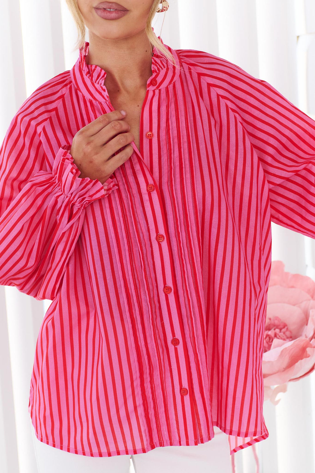Close up detail of a woman wearing the vibrant pink and red stripe minnie + MAXXIE Cece Shirt with ruffle collar.