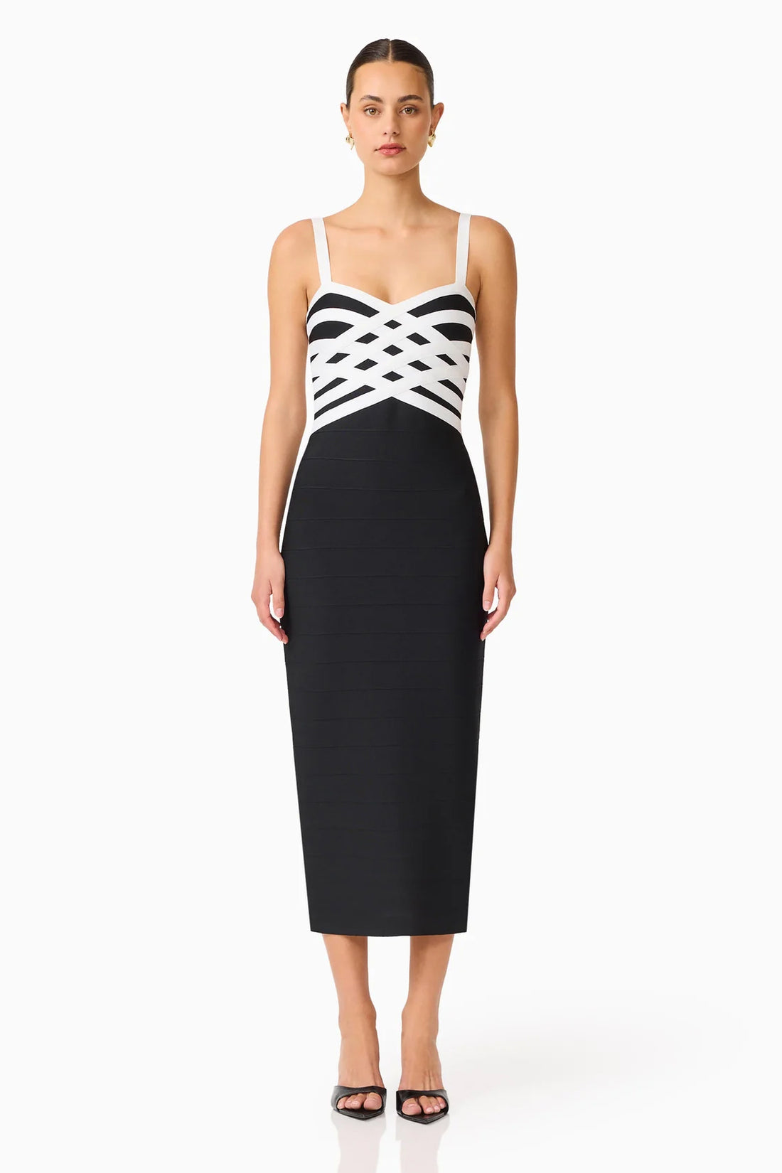 A model wearing the ELLIATT Ninette Column Midi Dress in Black & White with a white criss-cross strap pattern across the bodice, photographed against a plain white studio background.