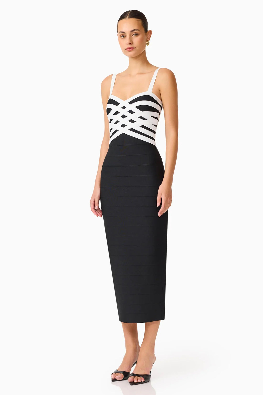 A model wearing the ELLIATT Ninette Column Midi Dress in Black & White with a white criss-cross strap pattern across the bodice, photographed against a plain white studio background.