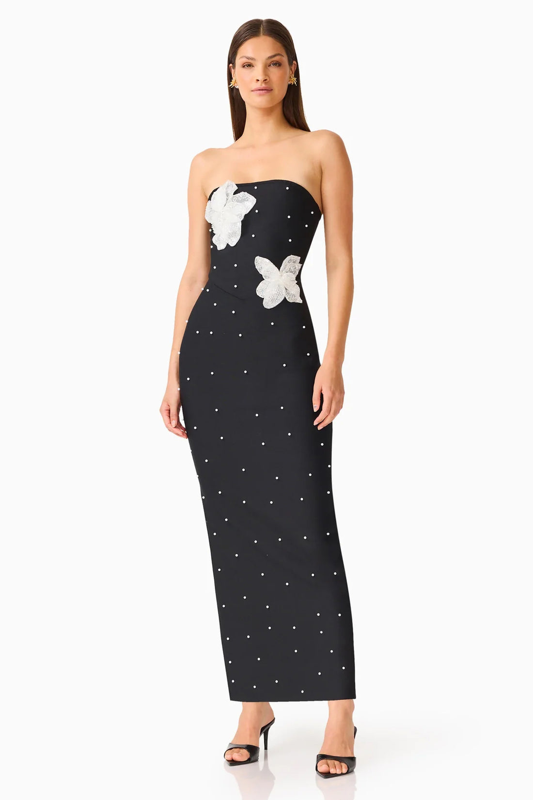 A woman modelling the ELLIATT Natasia embellished strapless black maxi dress with white floral appliquéflowers and pearl stud embellishments, photographed against a plain white studio background.