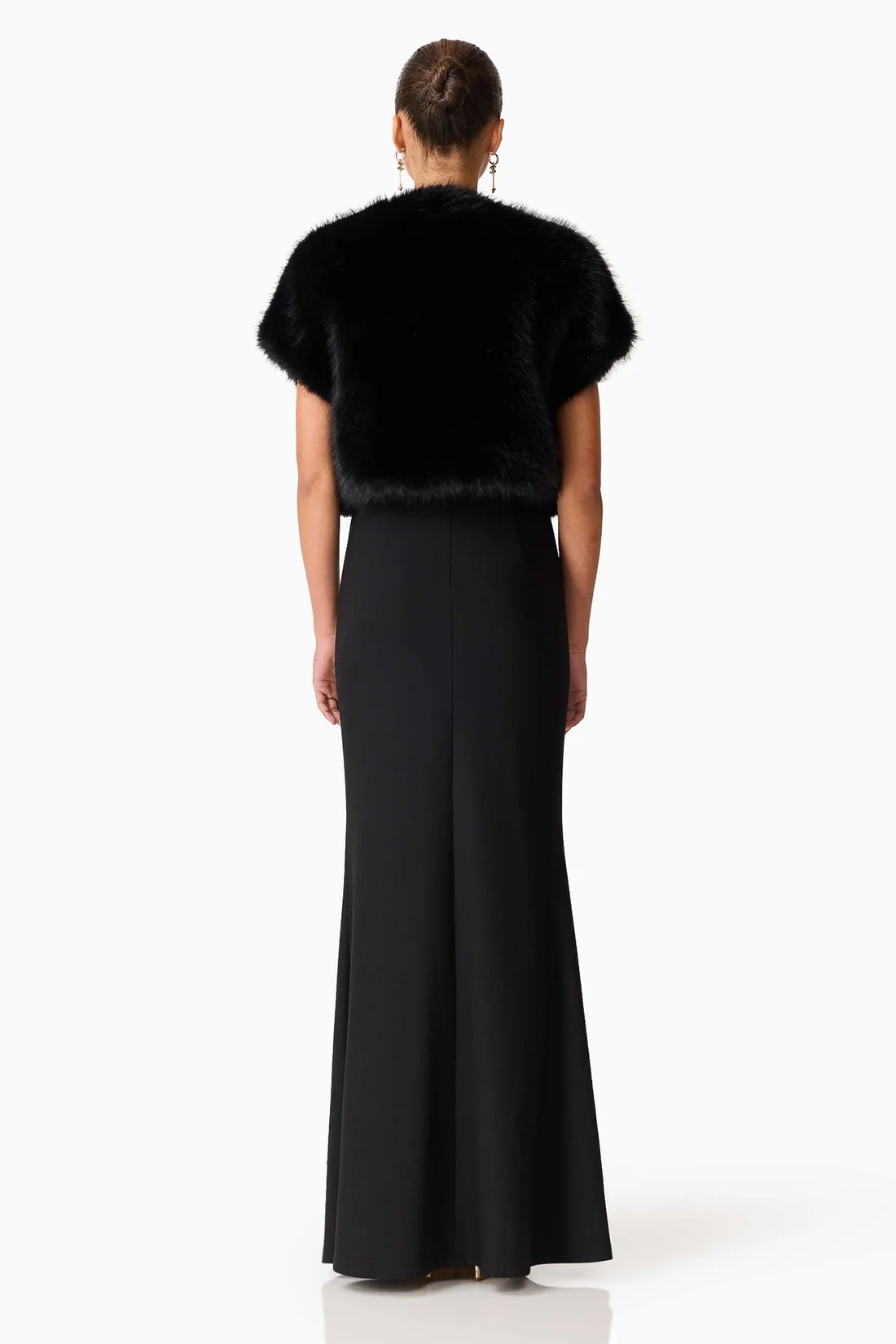 Back view of a oman wearing the ELLIATT black faux fur Lucyna bolero over the long black Veda gown