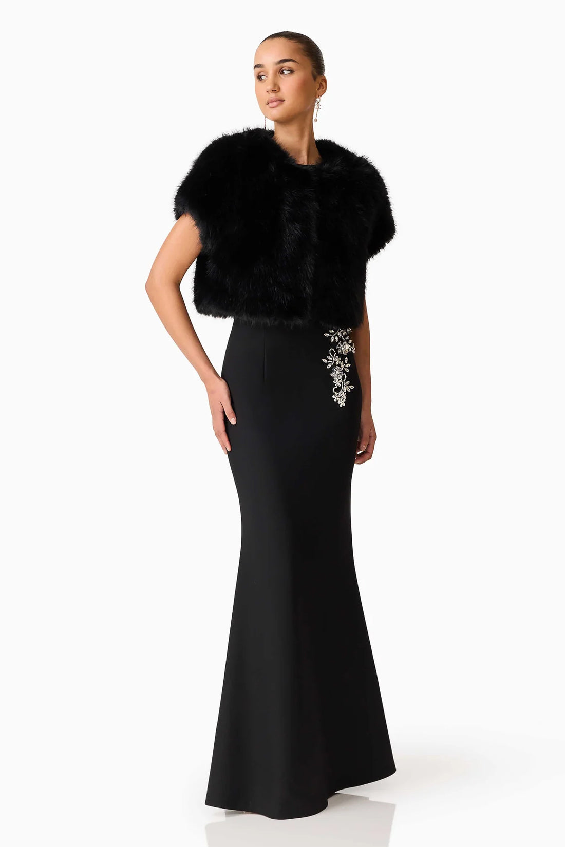 Full length of woman wearing the ELLIATT Veda Gown with diamante embellishments and the Lucyna short sleeve bolero in black faux fur
