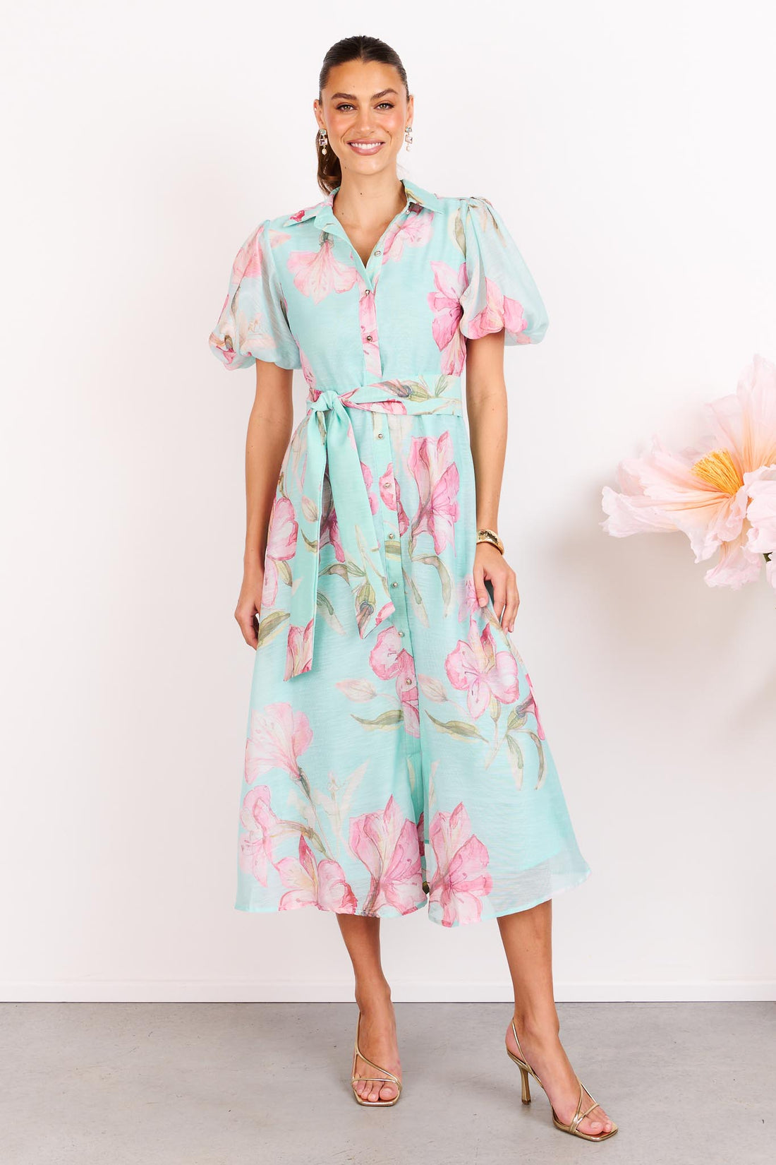 Woman wearing the minnie + MAXXIE La Belle aqua midi event dress with short puff sleeves and a matching waist tie.