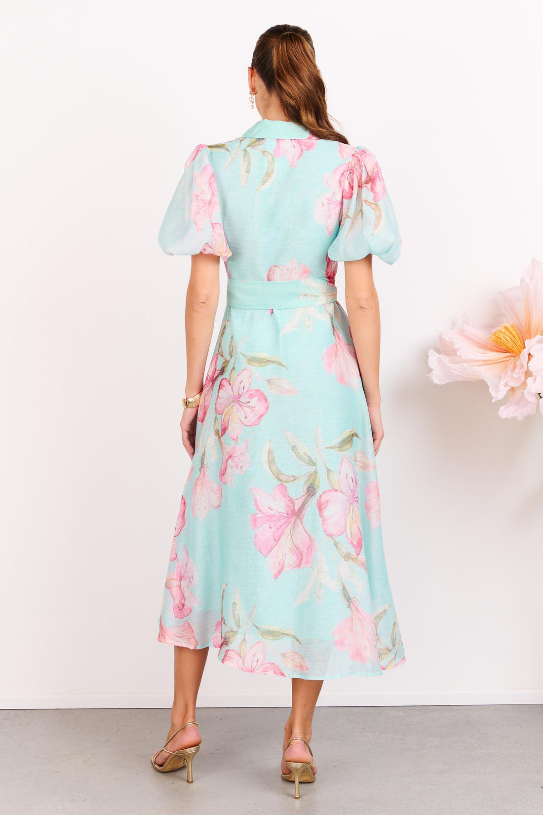 Back view of a woman wearing the minnie + MAXXIE La Belle aqua midi event dress with short puff sleeves and a matching waist tie.
