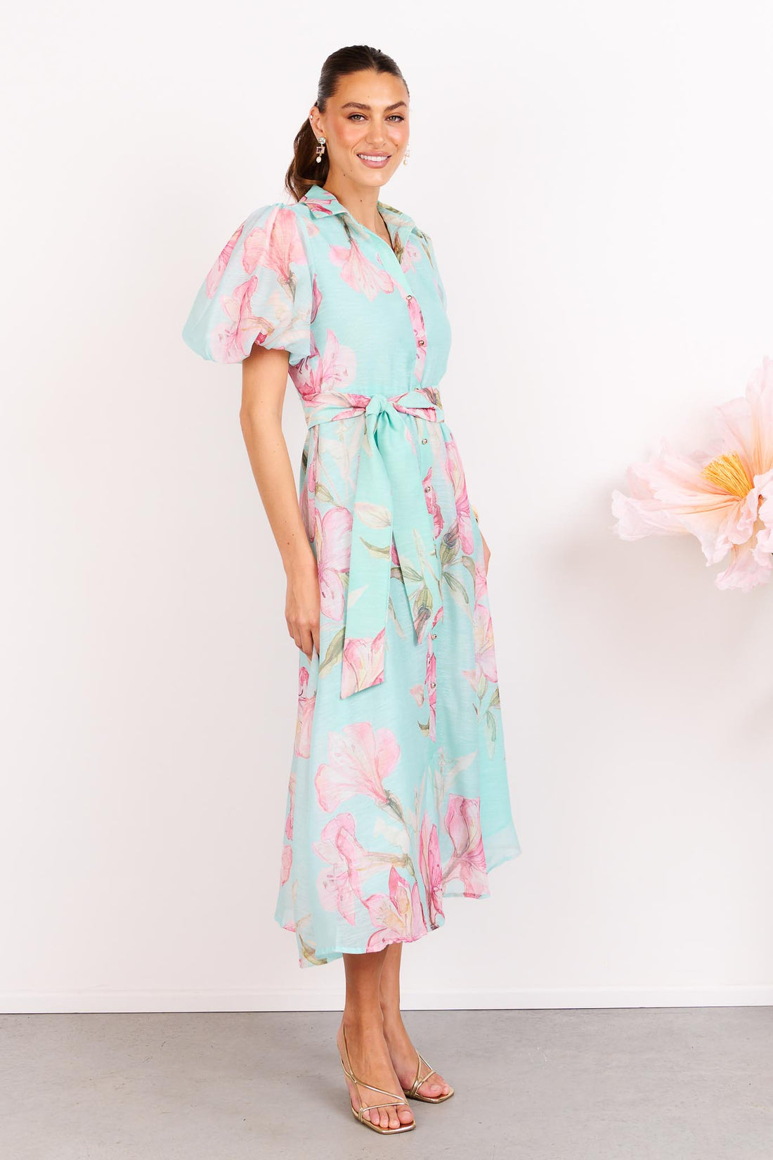 Woman wearing the minnie + MAXXIE La Belle aqua midi event dress with short puff sleeves and a matching waist tie.