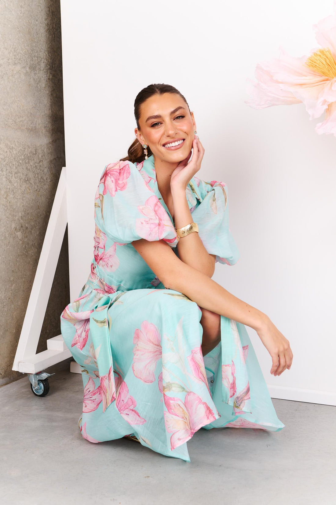 Woman wearing the minnie + MAXXIE La Belle aqua midi event dress with short puff sleeves and a matching waist tie.