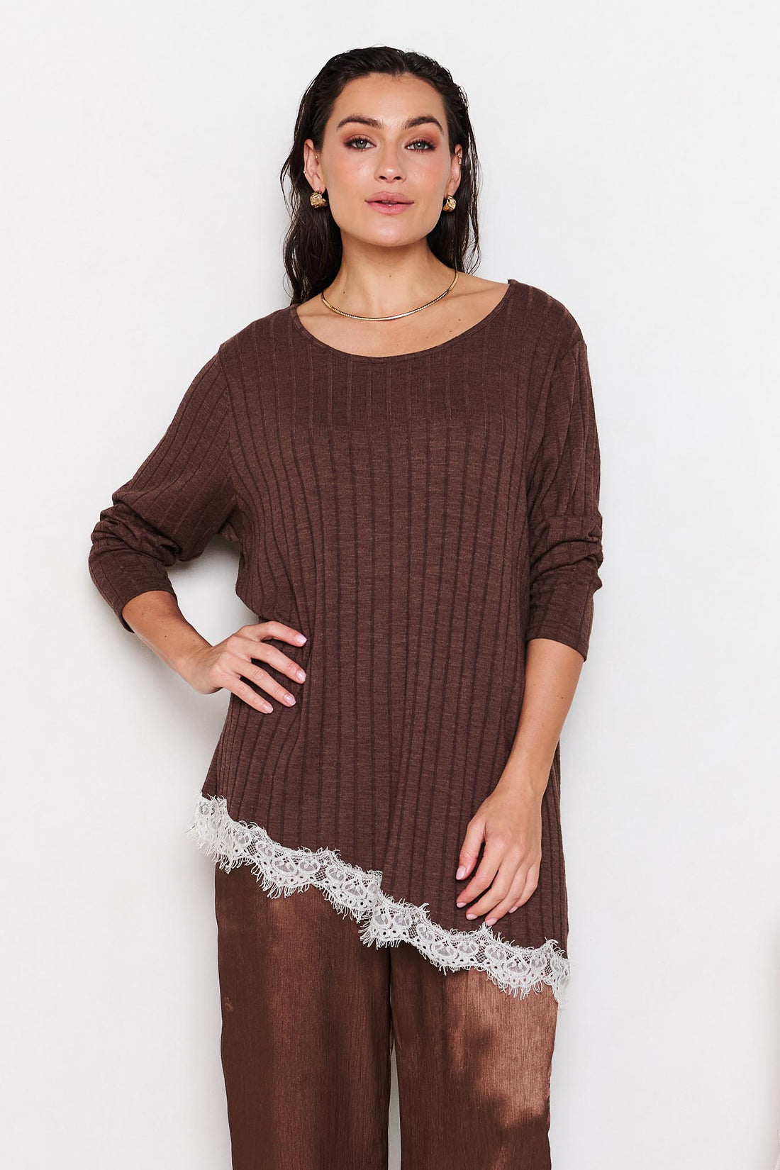 Woman wearing a brown ribbed sweater with lace trim on a white background