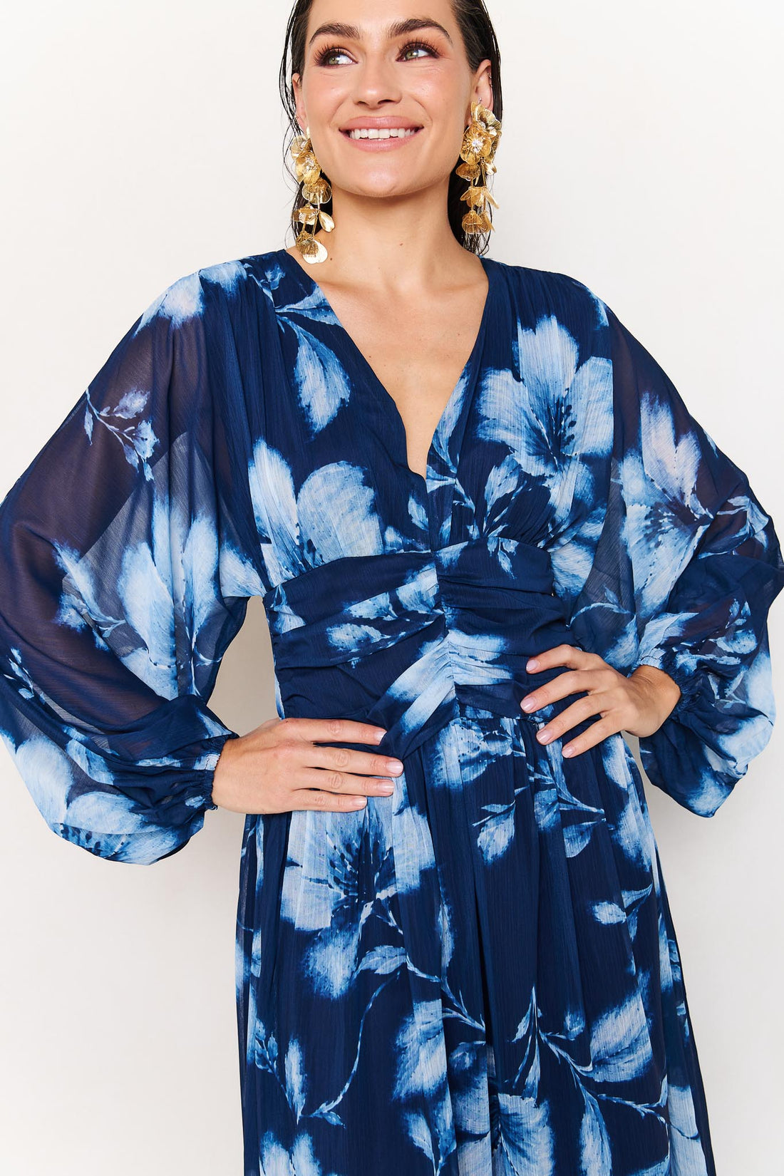 Close up of woman wearing the minnie + MAXXIE Lola blue floral event dress on a white background