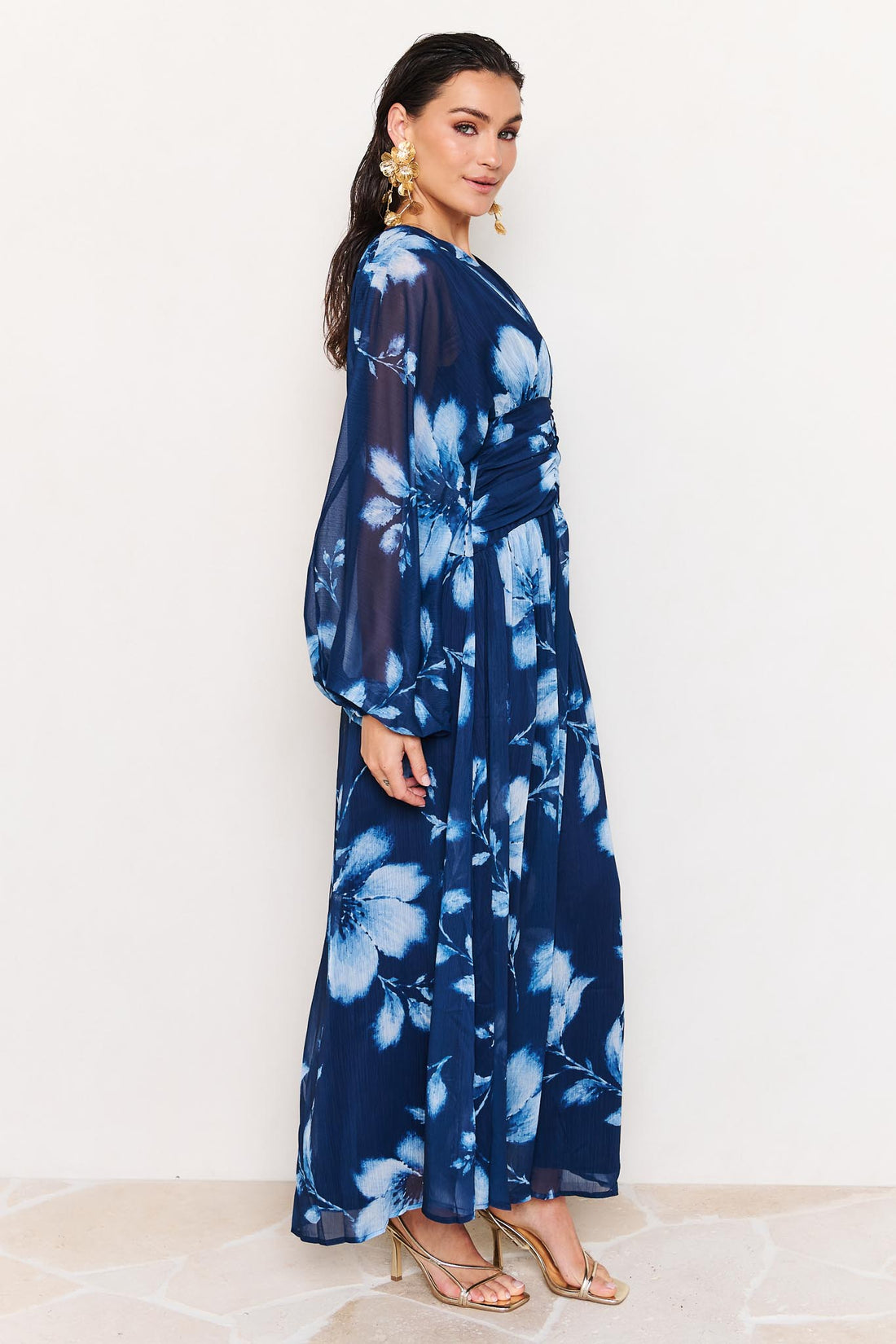 Side view of woman wearing the minnie + MAXXIE Lola blue floral event dress on a white background