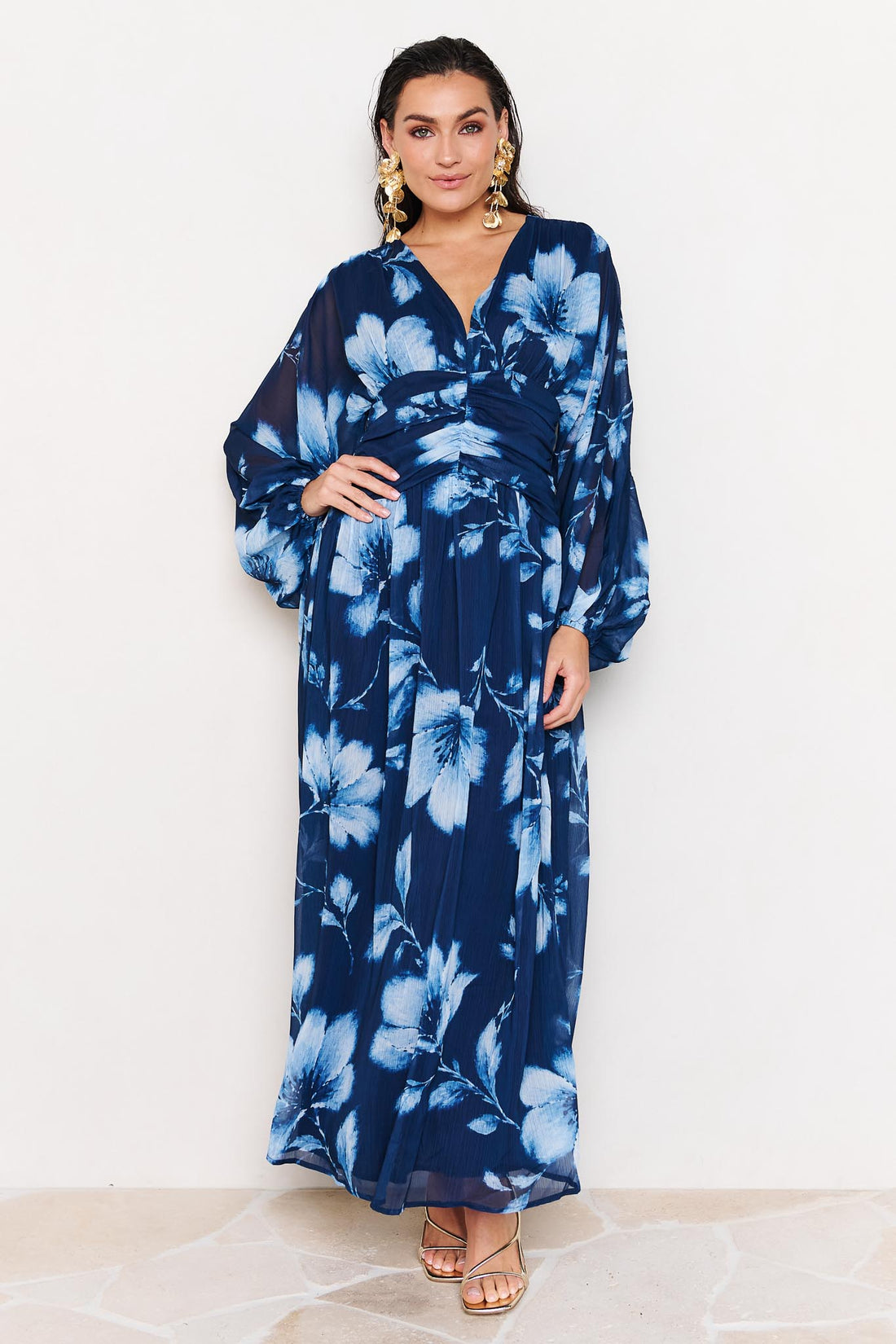 Woman wearing the minnie + MAXXIE Lola blue floral event dress on a white background