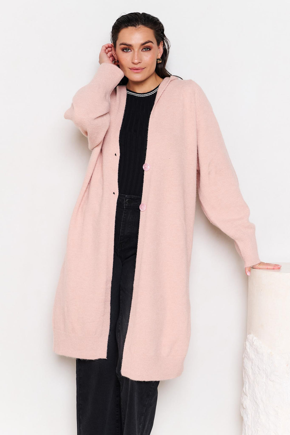 Woman wearing minnie + MAXXIE Lennox longline hooded cardi with black jeans in a white room