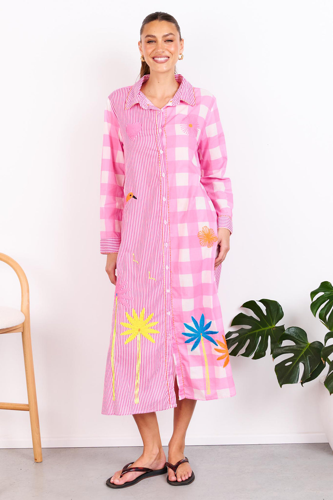 Woman wearing the minnie + MAXXIE Lovely Day Cotton midi shirt dress with long sleeves featuring a pink stripe and gingham print with neon embroidery.