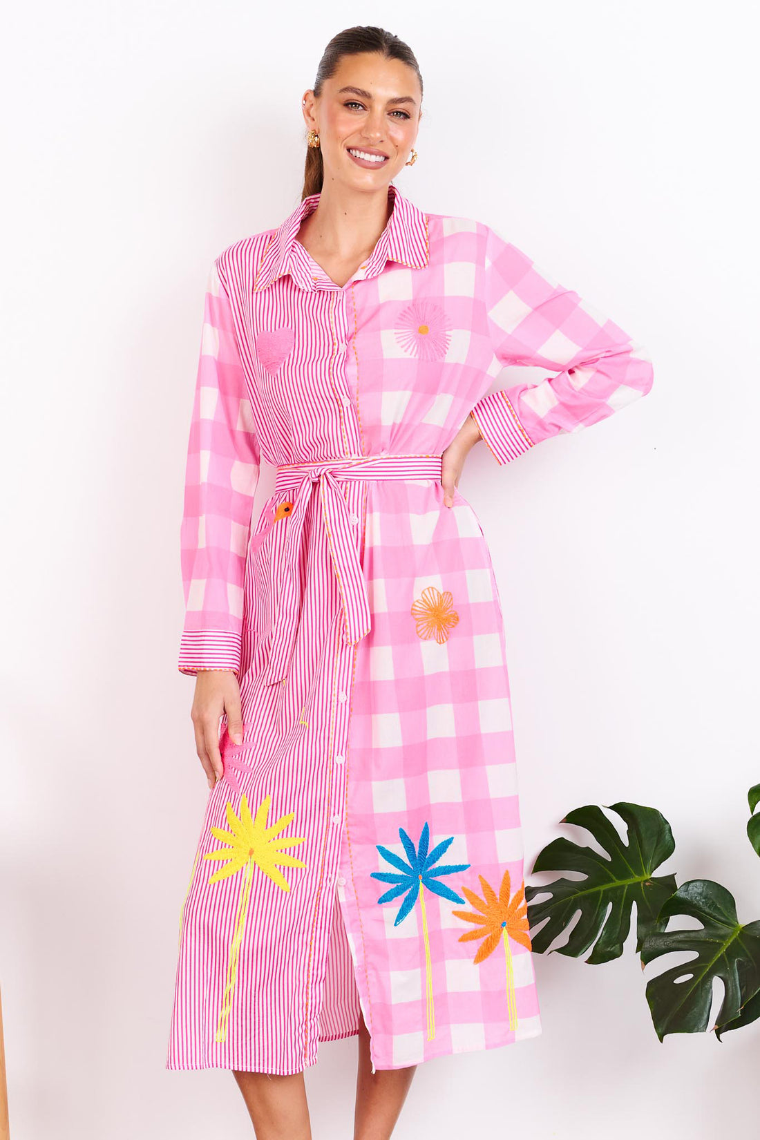 Woman wearing the minnie + MAXXIE Lovely Day Cotton midi shirt dress with long sleeves featuring a pink stripe and gingham print with neon embroidery and a matching waist tie.