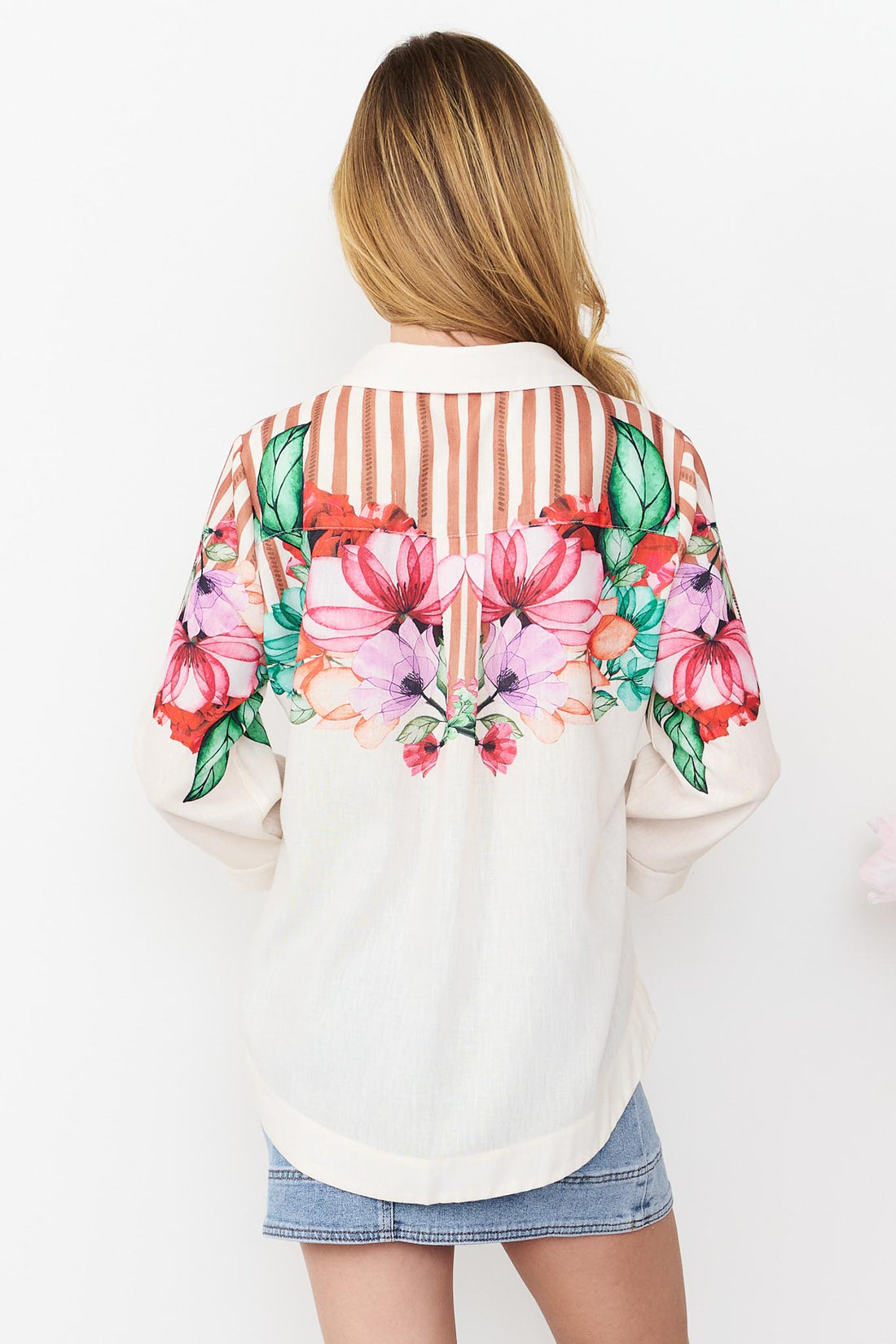 Back view of Mia Shirt in cinnamon with colourful floral patterns and stripes and a denim skirt