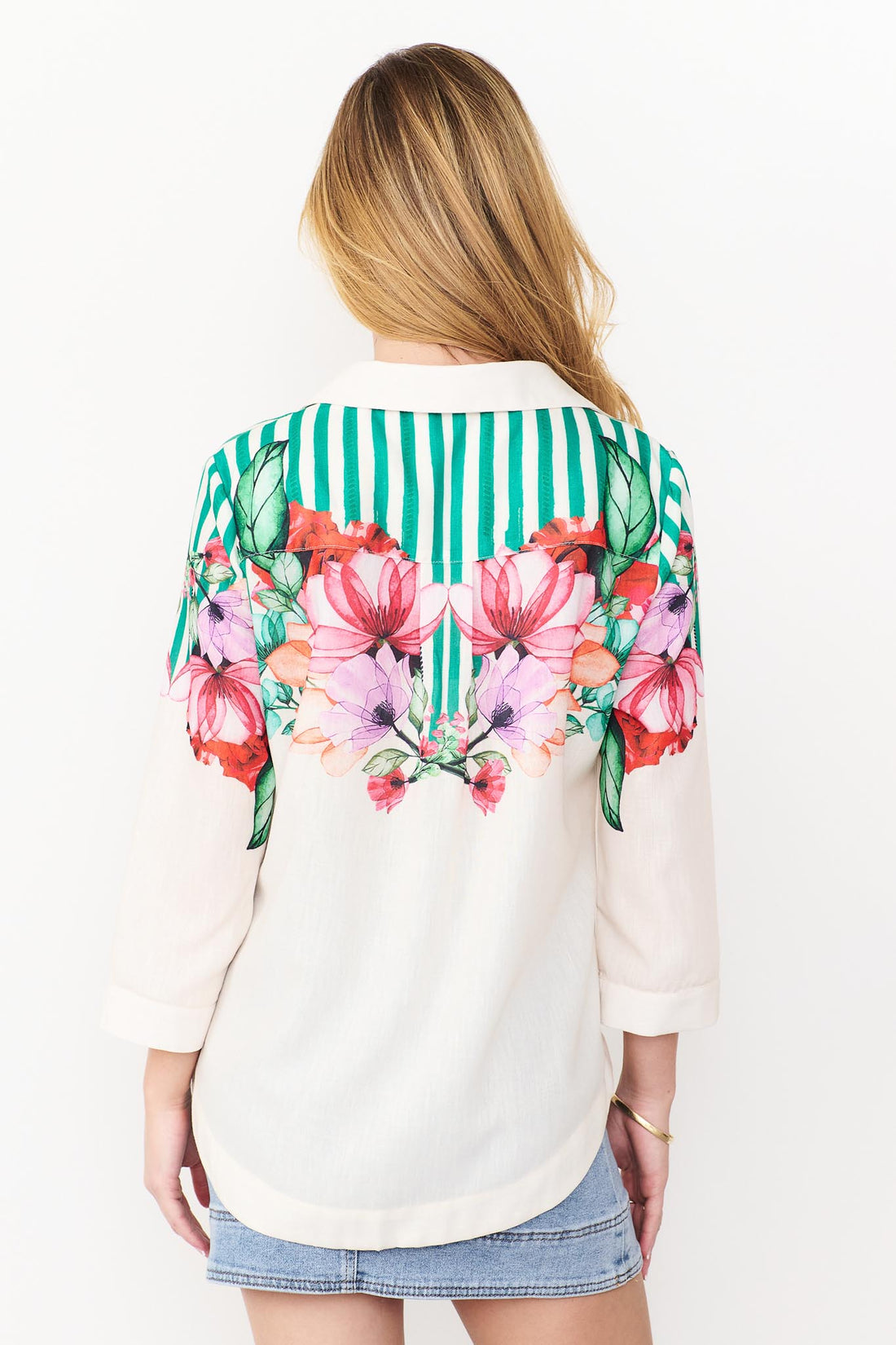 Back view Mia Shirt in green with colourful floral patterns and stripes and denim skirt.