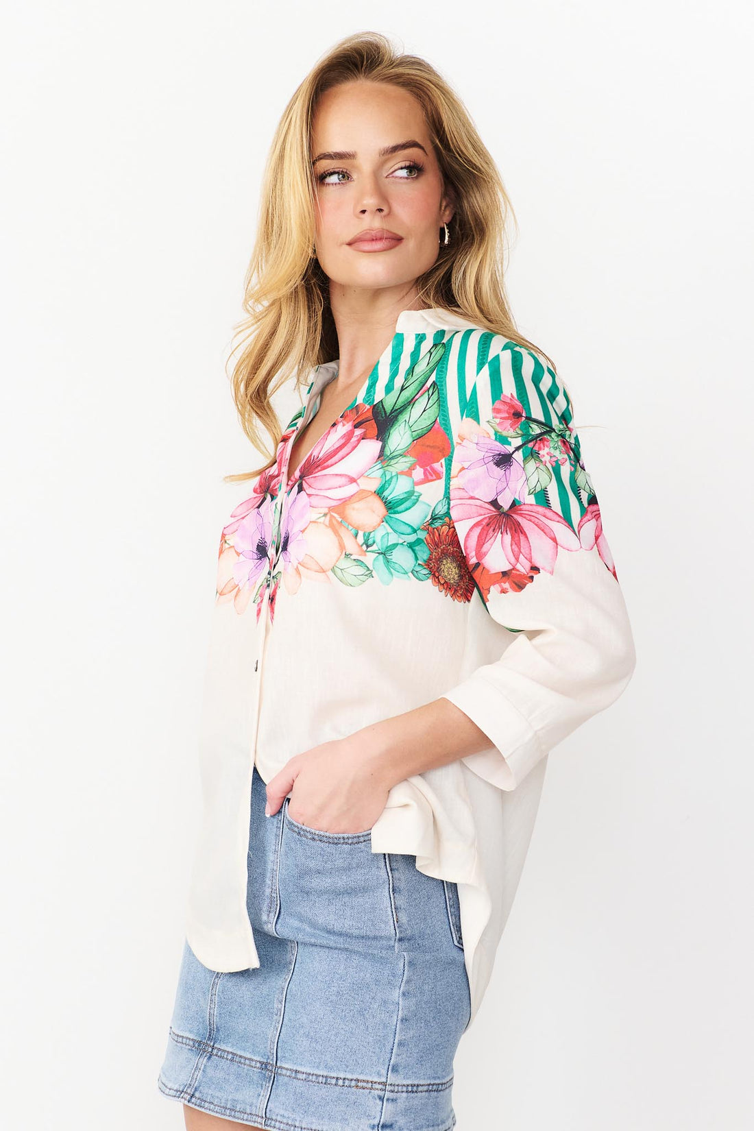 Side view Mia Shirt in green with colourful floral patterns and stripes and denim skirt.