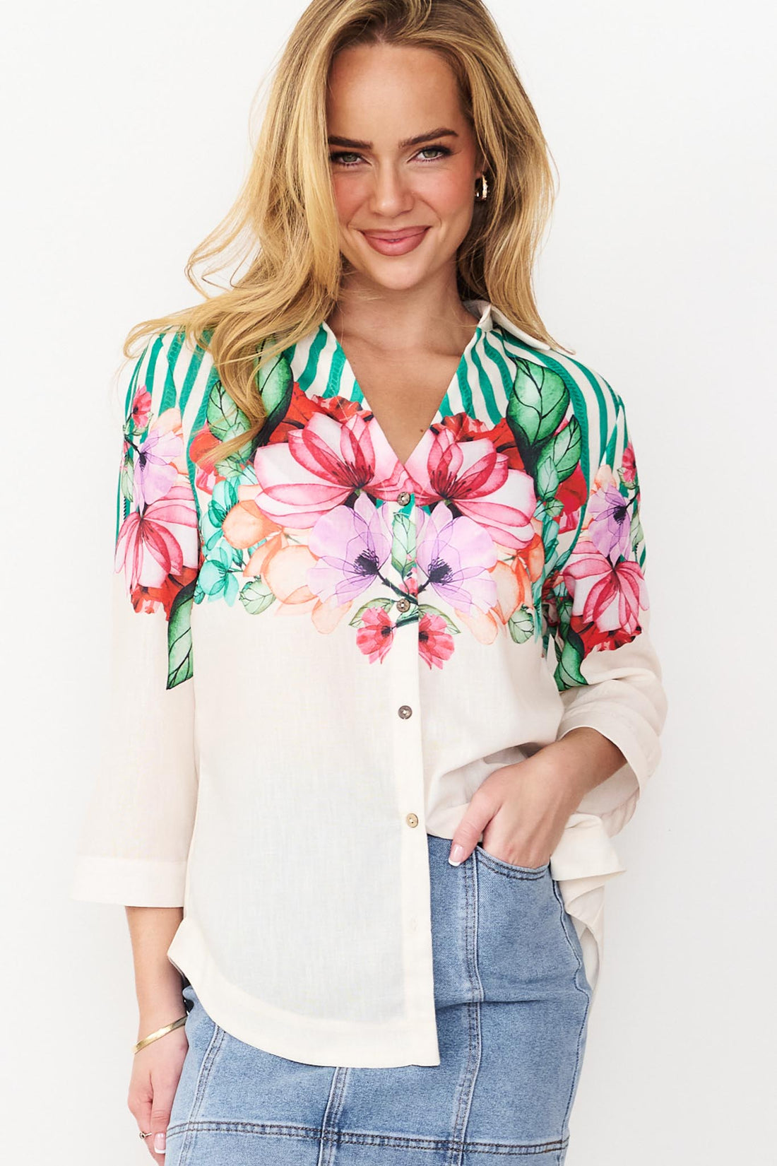 Close up of Side view Mia Shirt in green with colourful floral patterns and stripes and denim skirt.