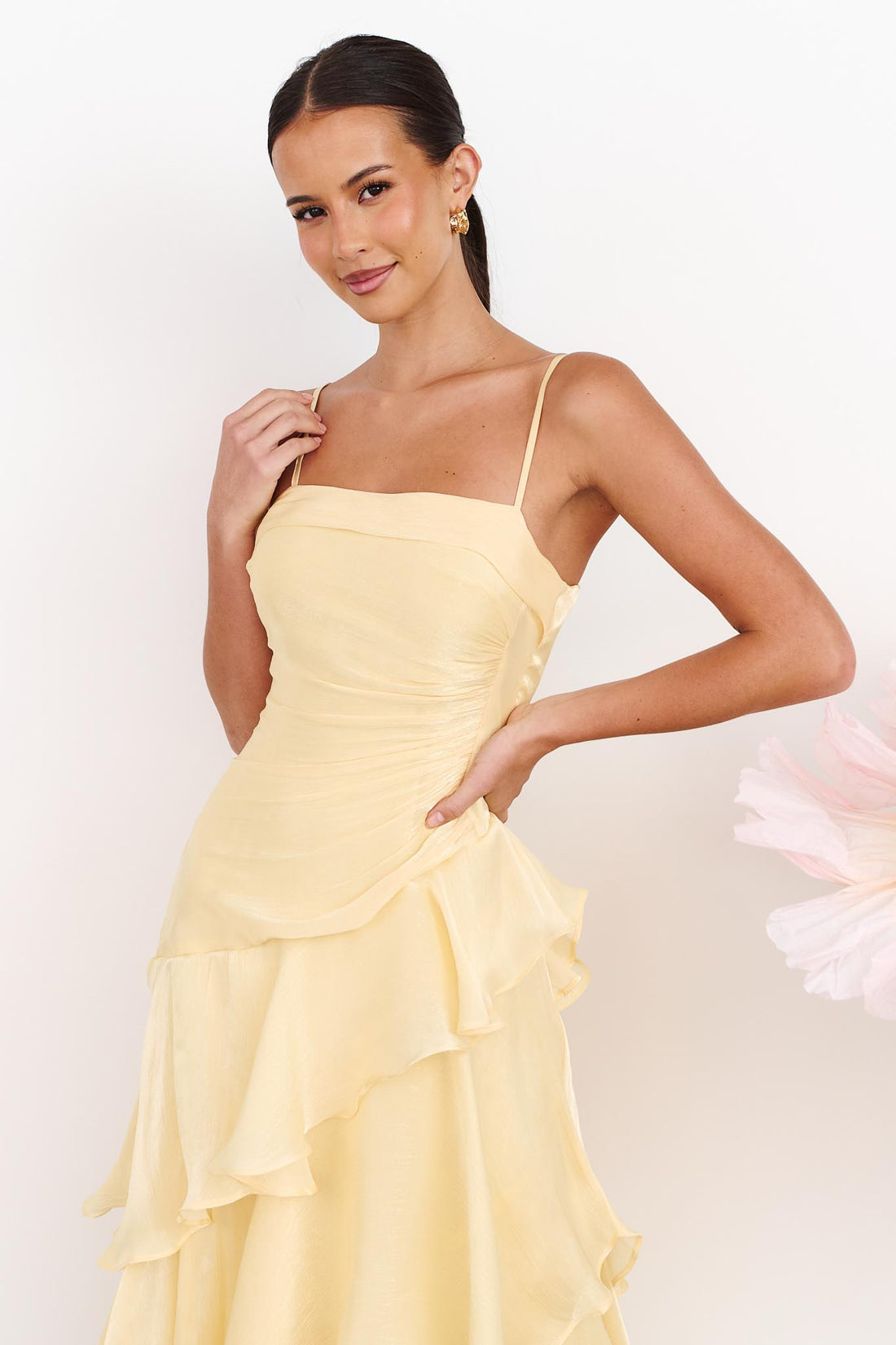 A woman wearing the minnie + MAXXIE Monaco Maxi Dress in pale yellow with a ruched bodice and layered ruffle skirt.