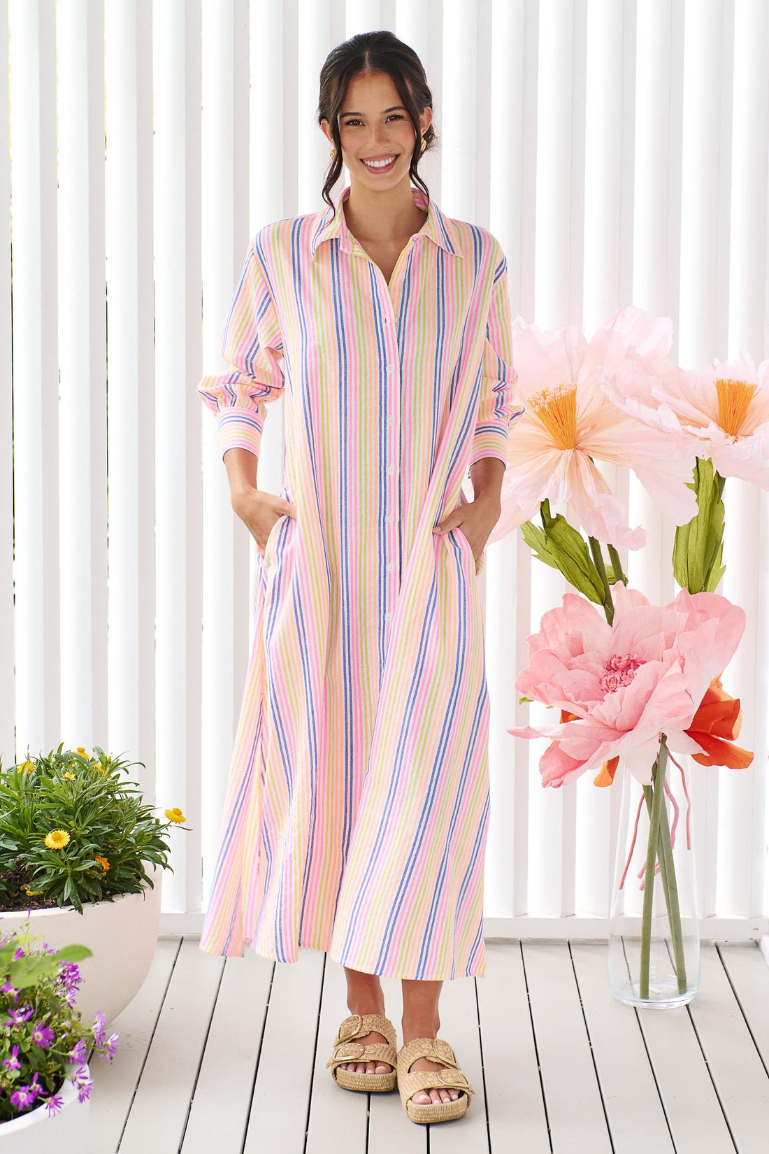 A woman wearing the minnie + MAXXIE Rio midi dress with 3/4 sleeves, colourful neon stripe print.