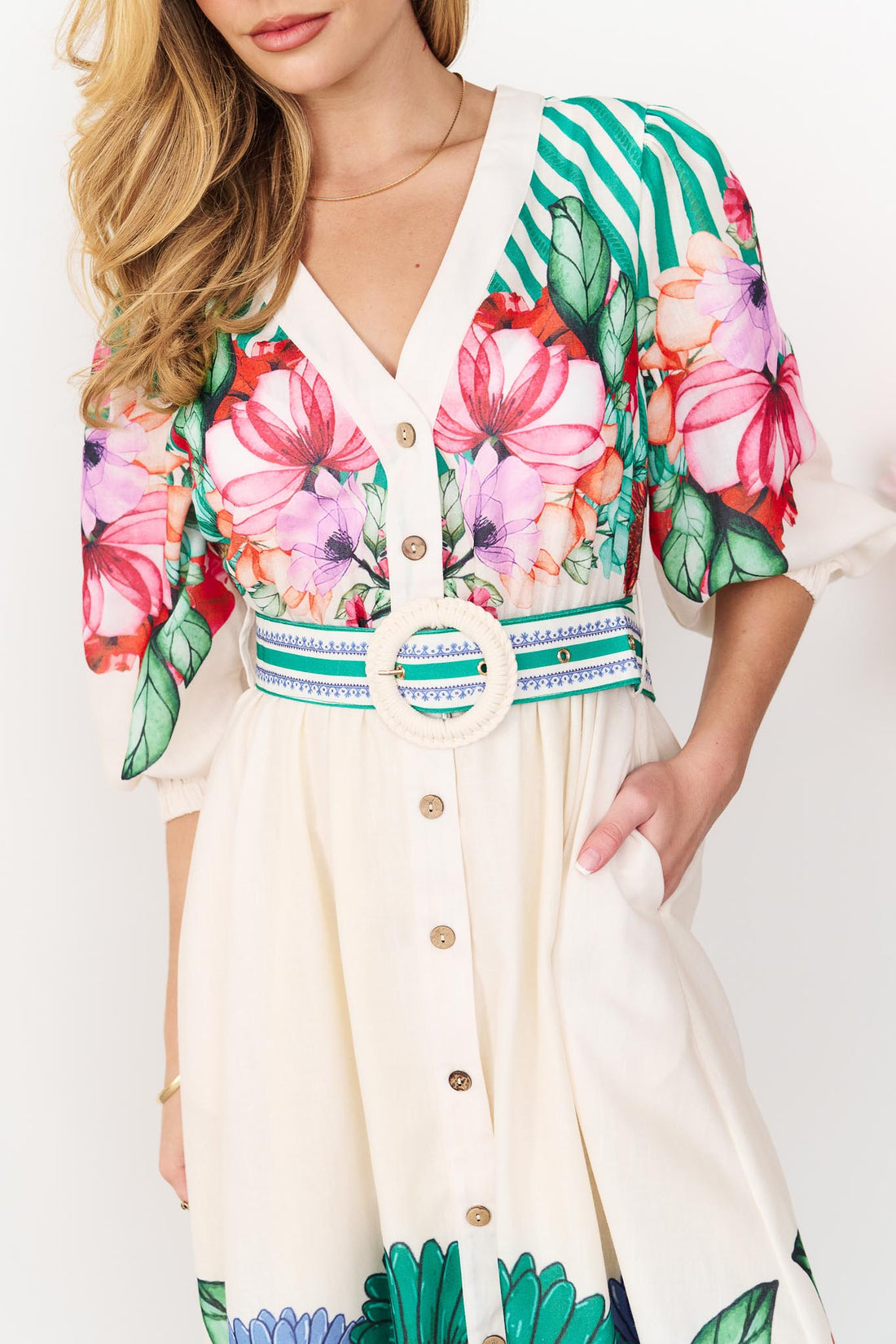Detail of the Rosabella dress with a bright floral and stripe print and white crochet buckle belt