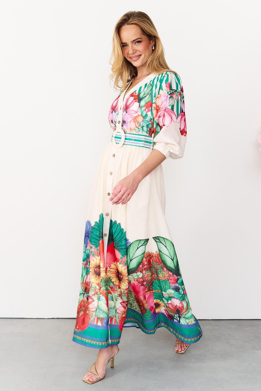 Side view of the Rosabella maxi shirt dress with a bright floral and stripe print and white crochet buckle belt
