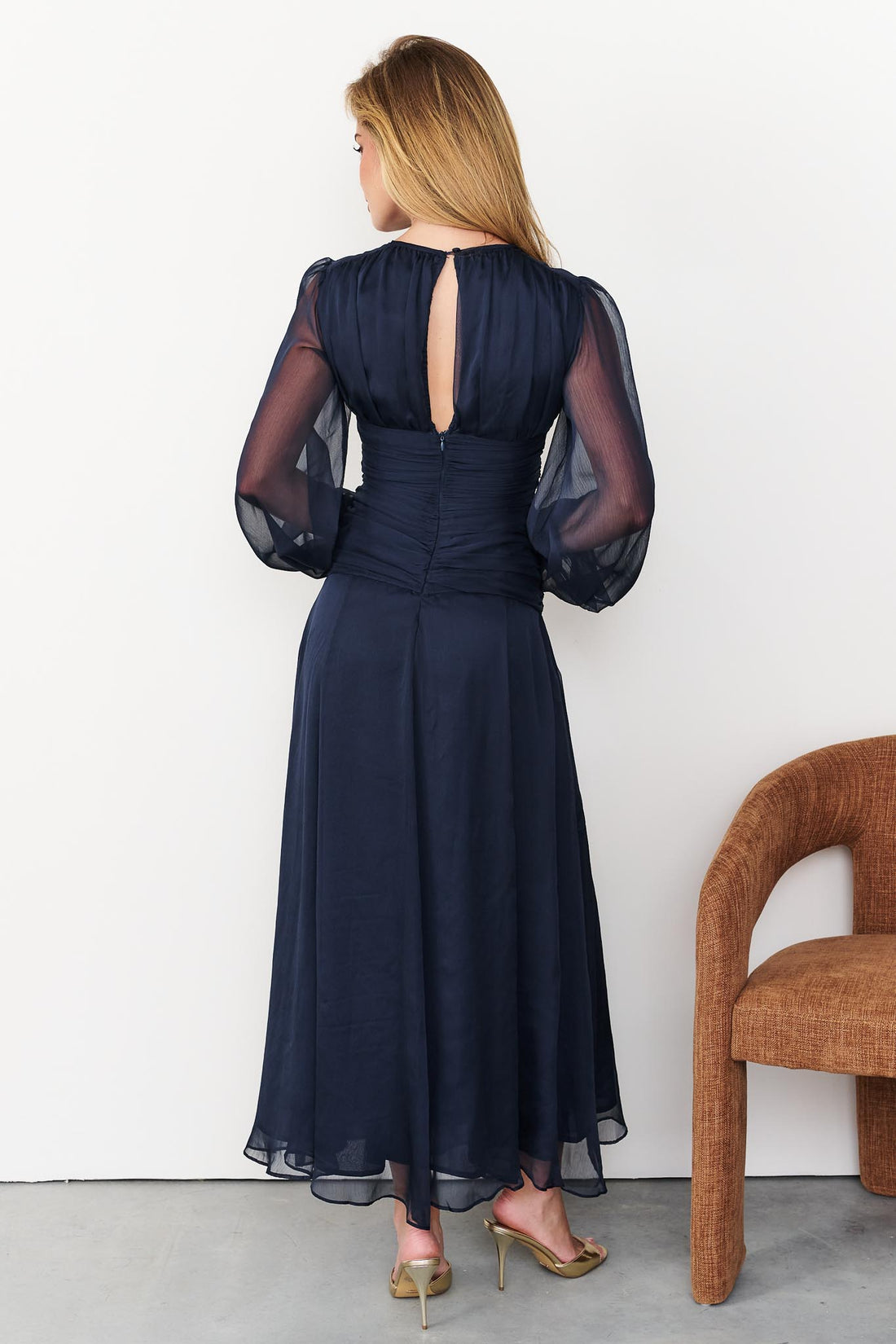 Back view of Sabine maxi event dress in navy blue with keyhole opening and long sheer sleeves.