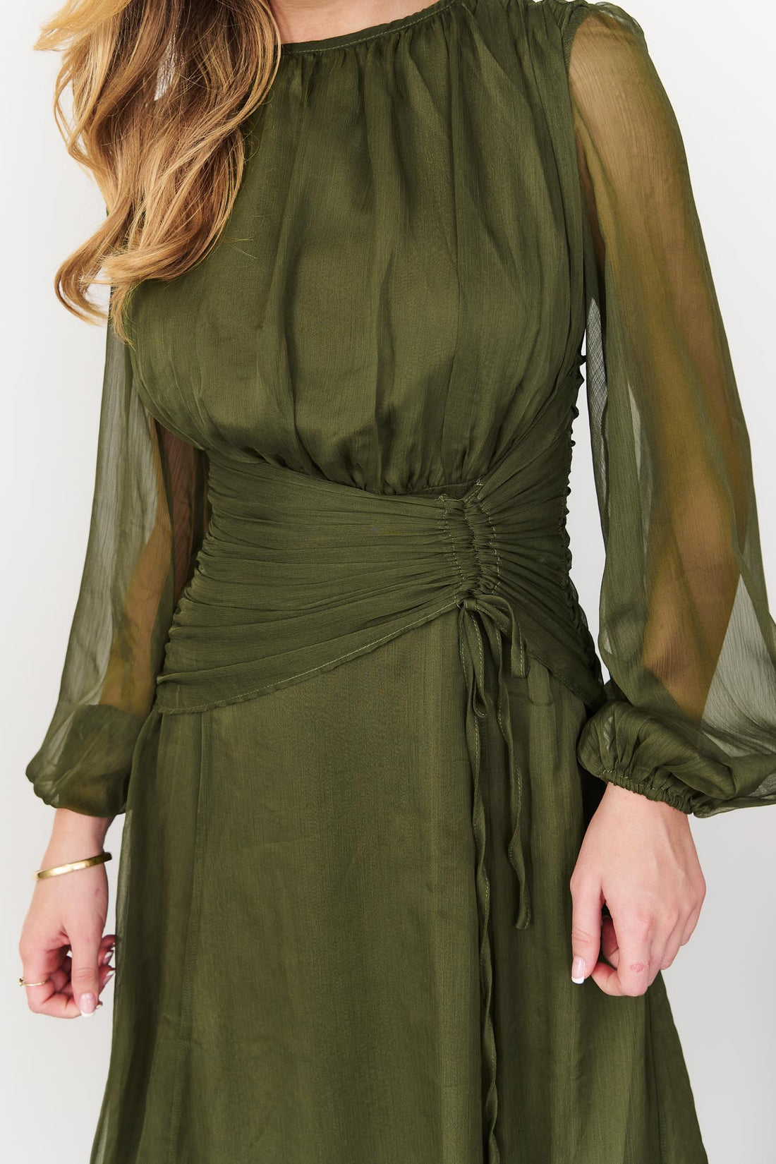 Detail of Sabine maxi event dress in olive green with a ruched tie waist and long sheer sleeves.