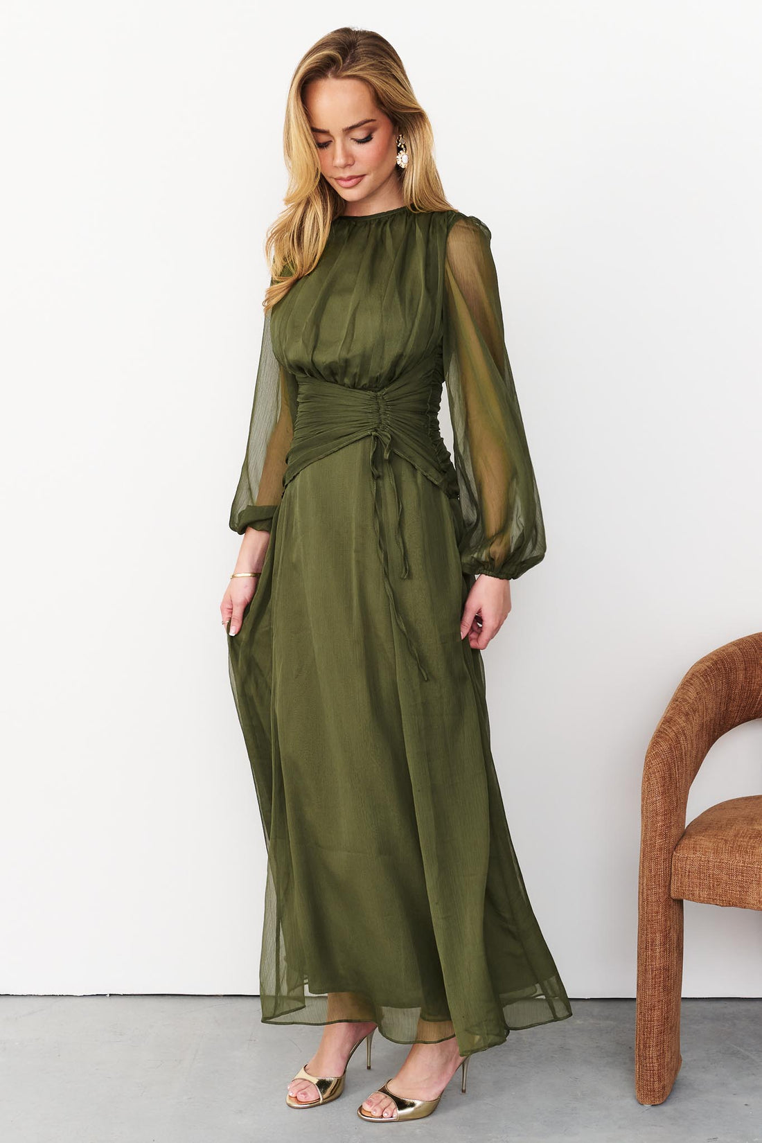 Sabine maxi event dress in olive green with a ruched waist and long sheer sleeves.