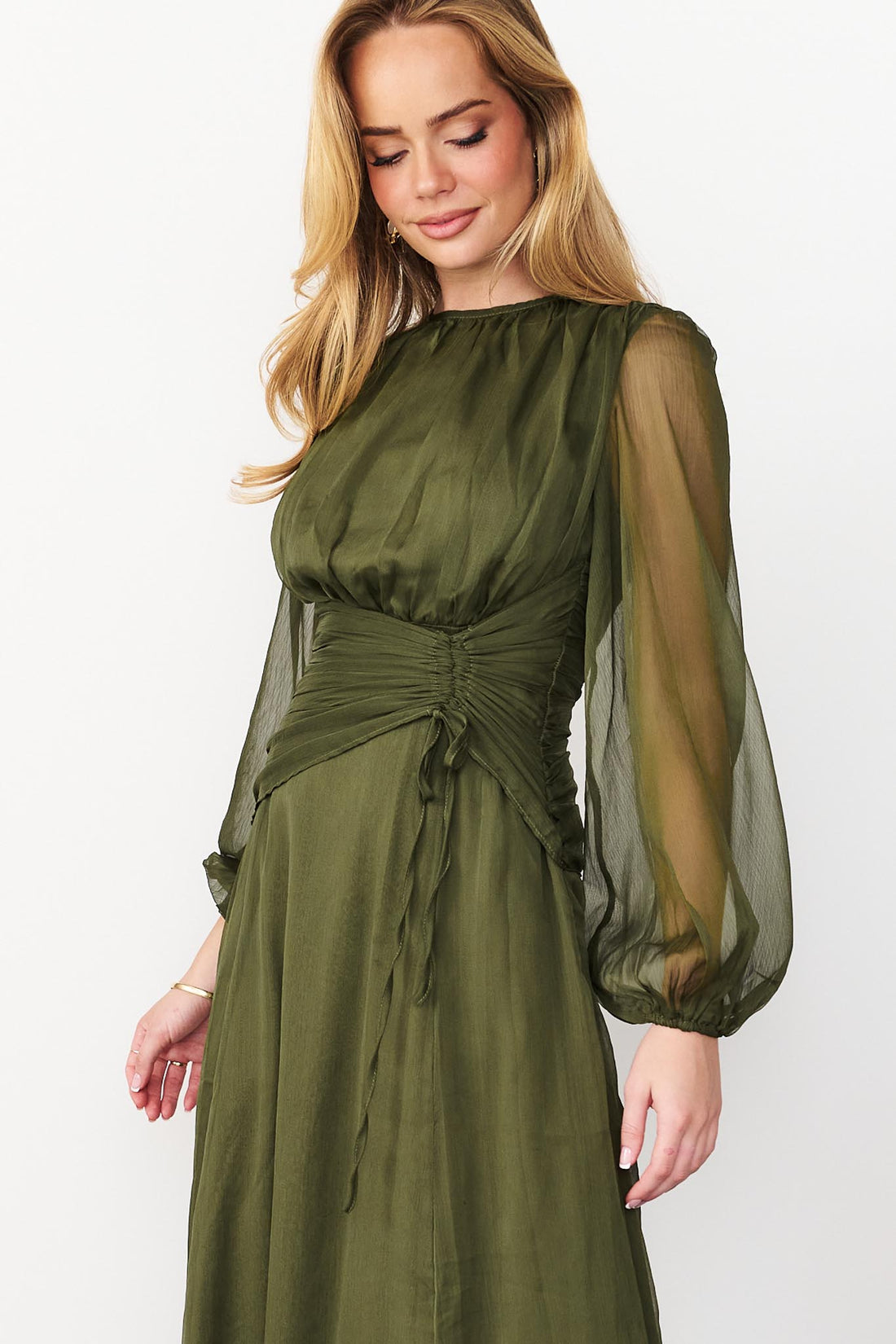 Close up of Sabine maxi event dress in olive green with a ruched waist and long sheer sleeves.