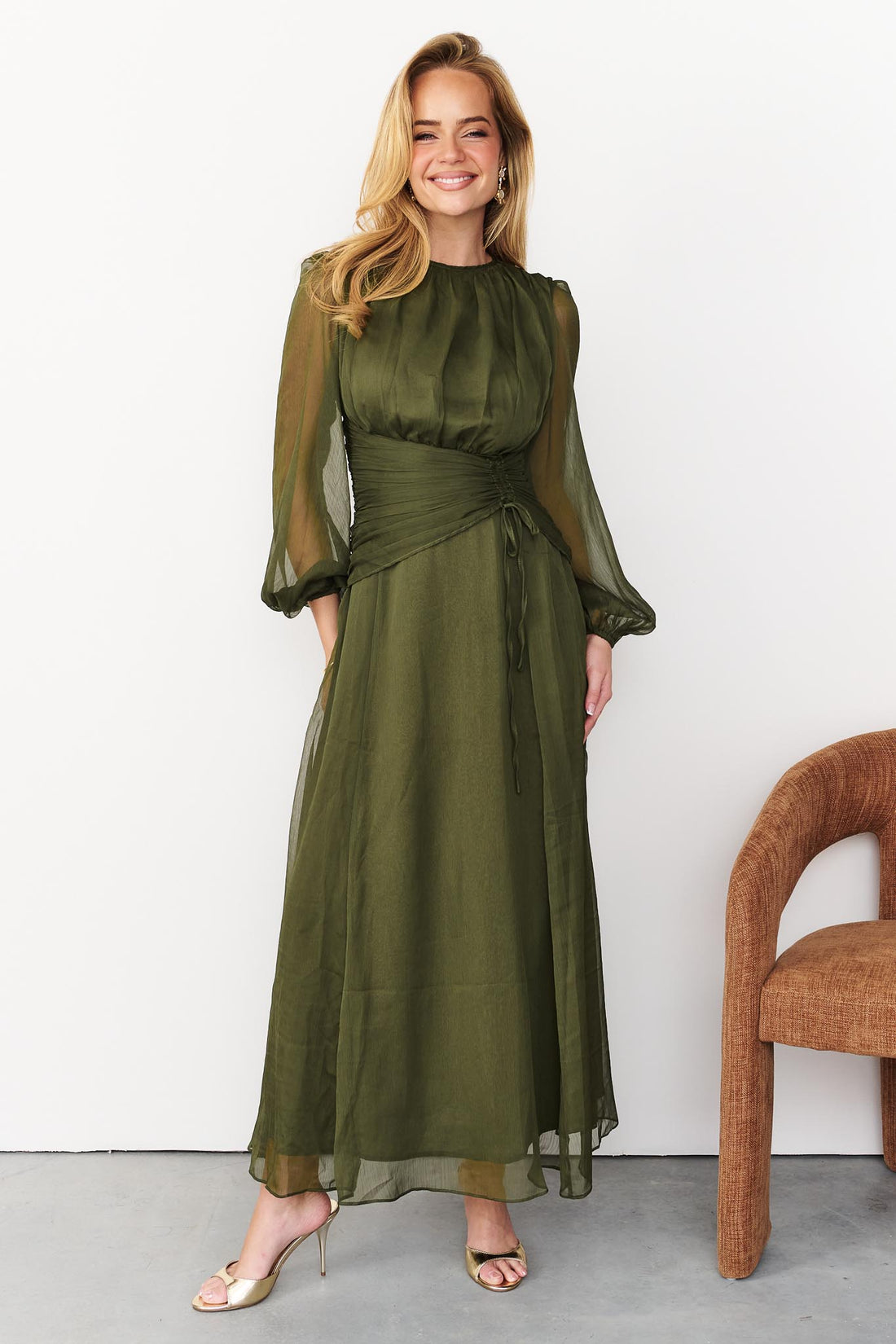Sabine maxi event dress in olive green with a ruched waist and long sheer sleeves.
