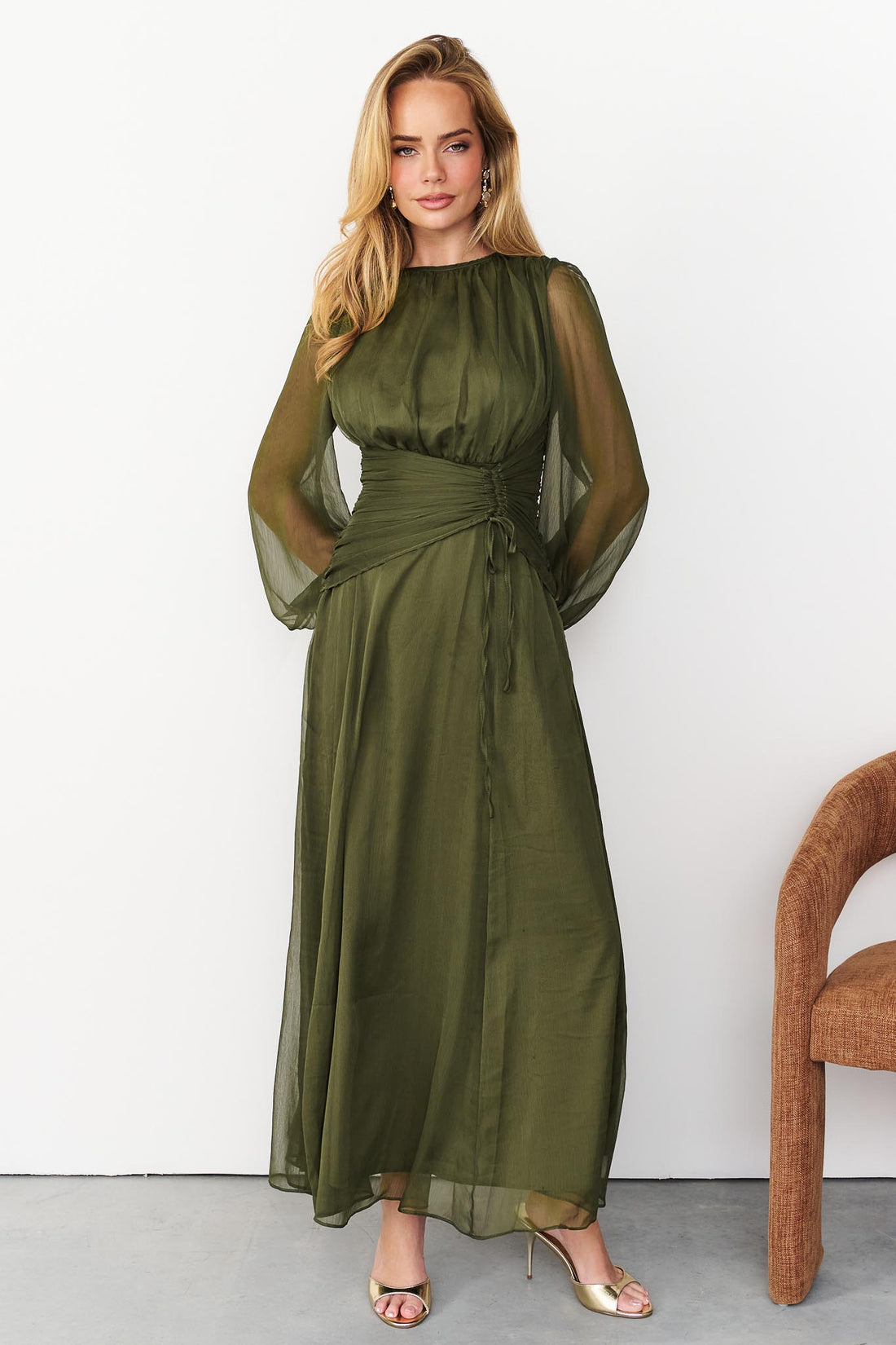 Sabine maxi event dress in olive green with a ruched waist and long sheer sleeves.