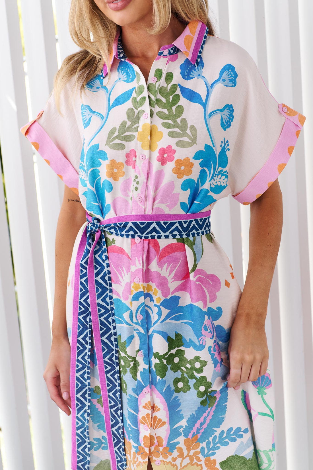 Close up of the colourful, short-sleeved minnie + MAXXIE Solana midi dress with a vibrant floral and geometric print.