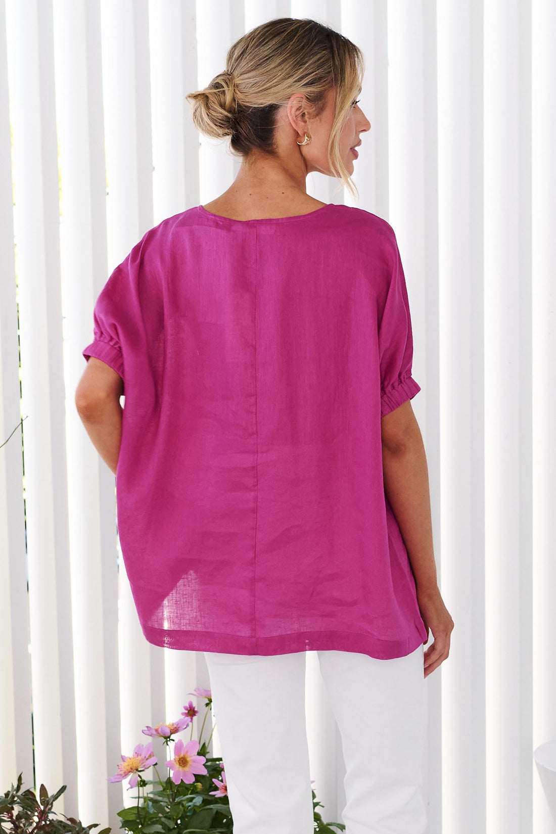 Back view of a woman wearing the minnie + MAXXIE studio linen top in Magenta pink