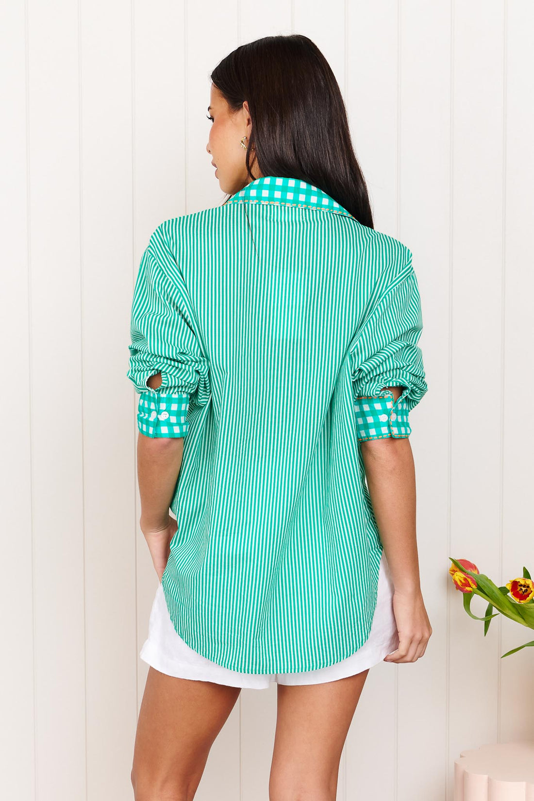 A woman wearing the minnie + MAXXIE Tutti Cotton Shirt, a bright green and white striped shirt with gingham trims.