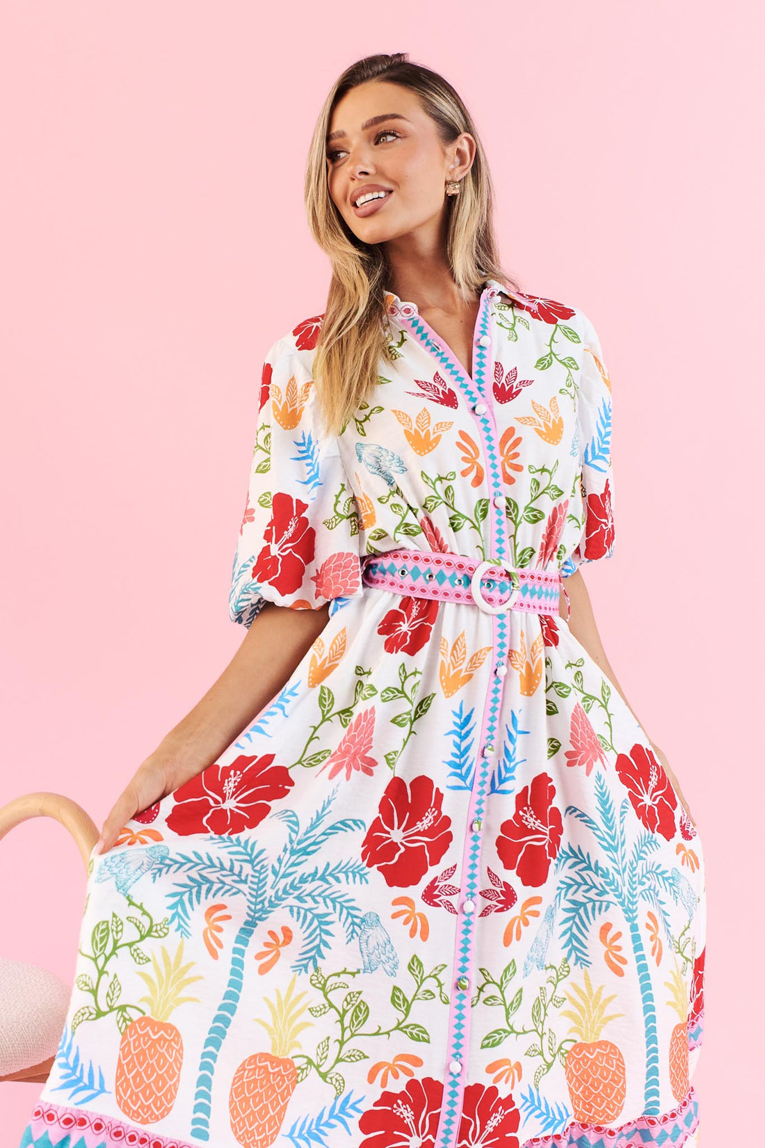Close-up of Valencia floral midi dress with pineapple print, short sleeves and matching belt on a pink background